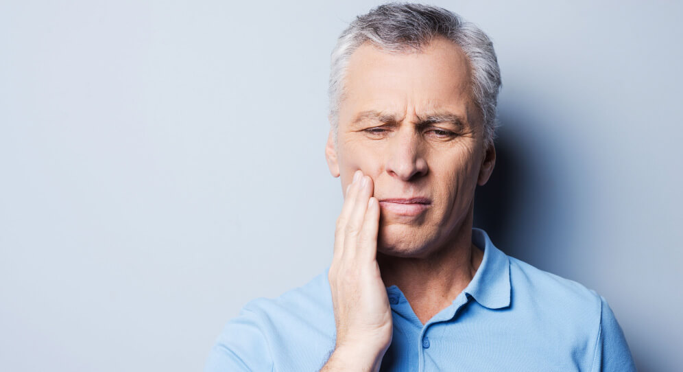 senior man holding side of mouth in pain