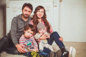 https://pixabay.com/photos/family-armchair-mom-sons-interior-2972218/ Two adults and two small children sitting on floor